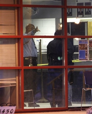 Detroit police point to a broken window at the precinct 6 building in northwest Detroit where a gunman walked into the police station and opened fire injuring three police officers, Sunday, Jan. 23, 2011.