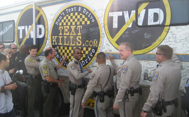 CHP and local police officers at Dodger Stadium Oct. 14, 2010, sign the exterior of a trailer that encourages people to pledge not to text while driving.