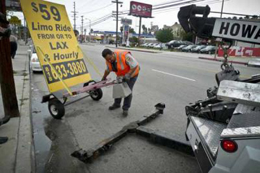 An advertising trailer is towed away by police along Vanowen blvd. in Woodland Hills. The city is cracking down on illegal advertising signs parked along the sides of roads throughout the San Fernando Valley.