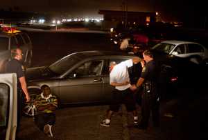 Officer Ryan Steele searches a suspect who was pulled over for reckless driving at Bolsa Chica State Beach in Huntington Beach.