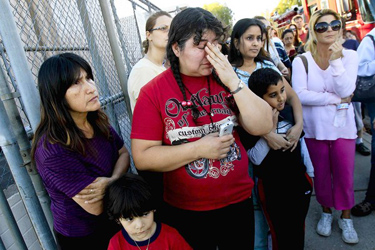 From left, Nancy Delgado, Pedro Antonio and his mother, Maria Perez, stand with others outside Hale Middle School in Woodland Hills, where helicopters drummed overhead and hundreds of officers searched for the gunman.