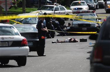 A suspect lies dead in an intersection in St. Paul, Minn., Saturday, May 1, 2010. The manhunt is over for a second suspect in St. Paul after he surrendered following the killing of a suburban police officer as he was sitting in his patrol car. Department of Public Safety spokesman Andy Skoogman says the second man surrendered in St. Paul and is in police custody. The first suspect was shot and killed by police earlier Saturday.