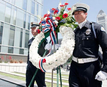 Two members of the LAPD Honor Guard carry a wreath with 203 carnations -- one for each officer killed in the line of duty.  The one red flower is for SWAT Officer Robert J. Cottle, who died this year in Afghanistan.