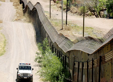 A U.S. Border Patrol agent drives along the steel wall separating the U.S. from Mexico.