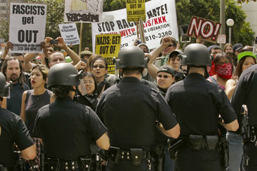 Police manage a group of counter-protesters as National Socialist Movement rally participants are escorted to their cars.