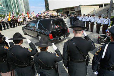 Police officers salute as a hearse carrying the body of one of two Miami-Dade police officers killed last week arrives for a memorial service at American Airlines Arena on Monday in Miami. Officers Amanda Haworth and Roger Castillo were killed Thursday when they were serving an arrest warrant.