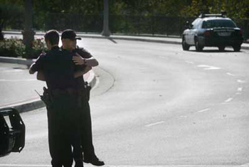 Riverside police Officer Derek Kopitch, right, shares a quick embrace with a fellow officer on Market Street in front of Fairmount Park near where Officer Ryan Bonaminio was shot and killed Sunday night. The suspect remains at large. Bonaminio would have been 28 on Thanksgiving.