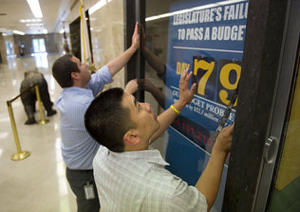 Jon Villalva, left, and Daniel Fong change numbers on a budget clock in the Capitol as the state breaks a record Friday by going 79 days beyond the start of the fiscal year without lawmakers approving a budget. Talks to close the $19 billion deficit resume Monday.