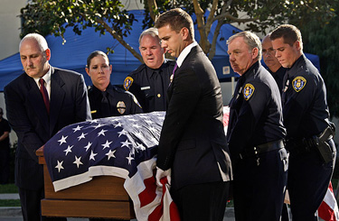 Pallbearers, including Conner Wilson, center, son of fallen San Diego Police Officer Christopher Wilson, carry his casket into Rock Church.