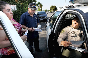 Deputy Jose Esparza, right, files a stolen-vehicle report for Maywood residents Angelina and Jose Martinez. The L.A. County Sheriff's Department took over patrols in the city July 1 after its police department was disbanded.