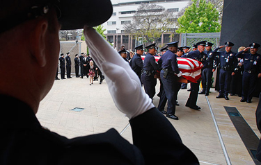 Officers stand at attention and salute as pallbearers carry the casket into the cathedral.