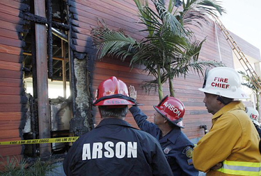 Los Angeles Fire Department arson investigators look over the remains of a house fire in the Hollywood Hills section of Los Angeles Thursday, Feb 17, 2011. A firefighter was battling for his life Thursday after a ceiling collapsed at the burning home, injuring him and five others.